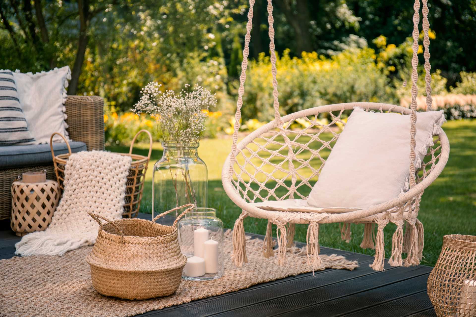 Cozy outdoor patio with hanging chair, cushions, and natural decor
