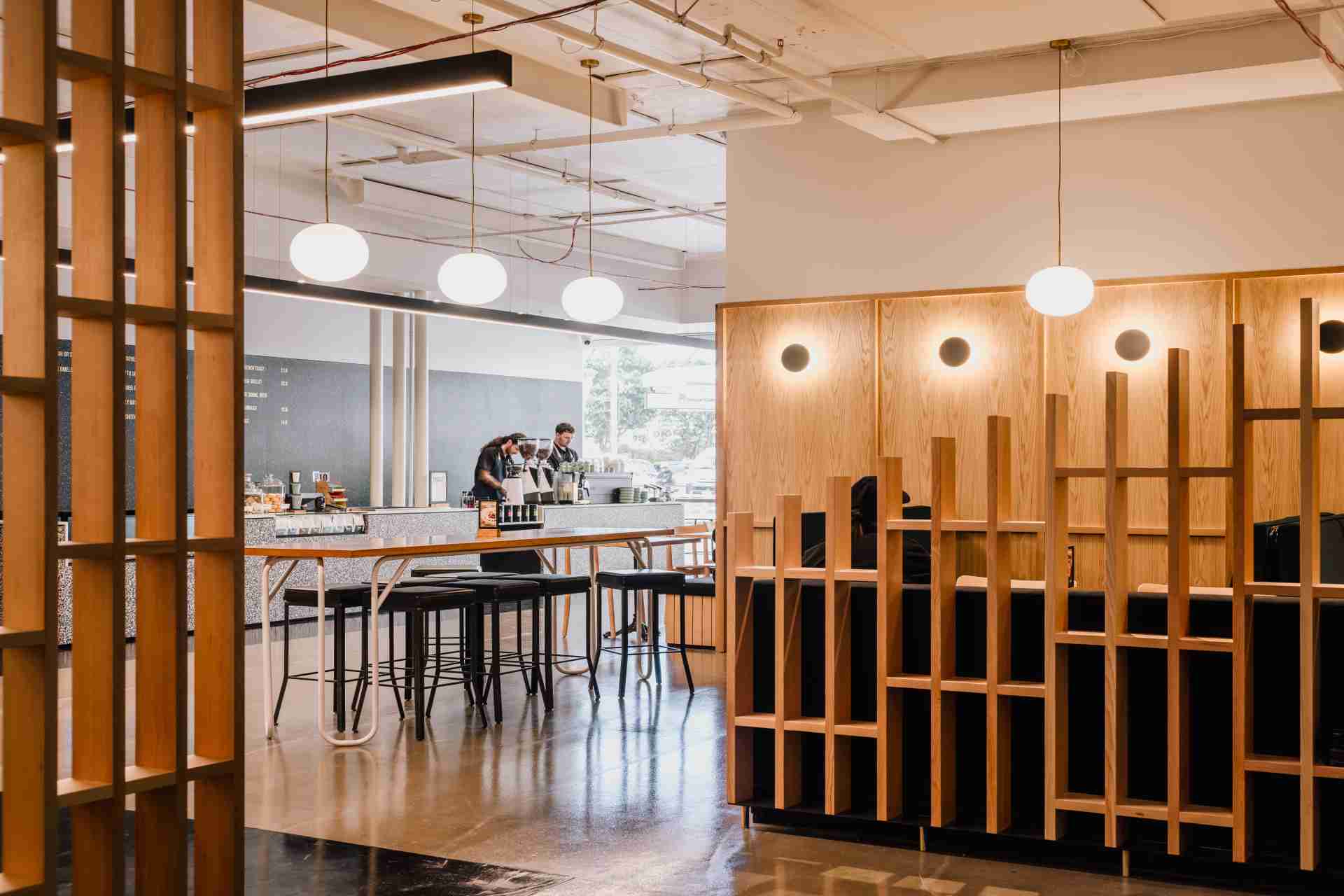 Modern café interior with wood partitions, bar seating, and hanging globe lights