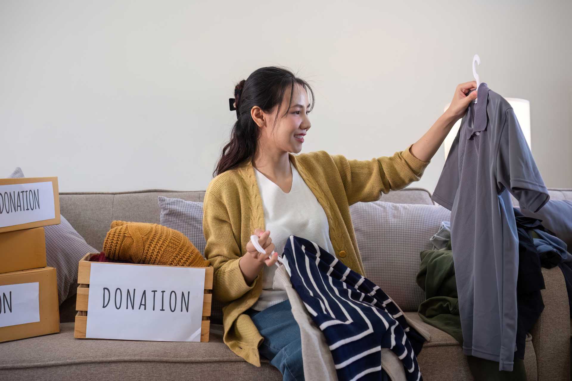 Woman sorting clothes into a donation box at home