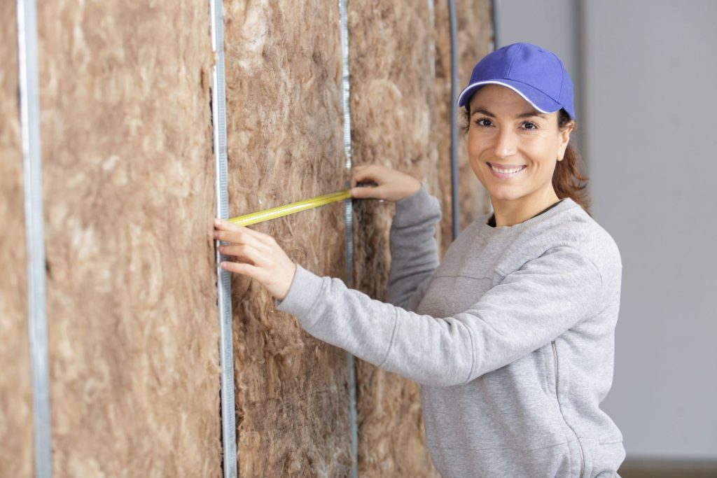 A woman measuring wall insulation