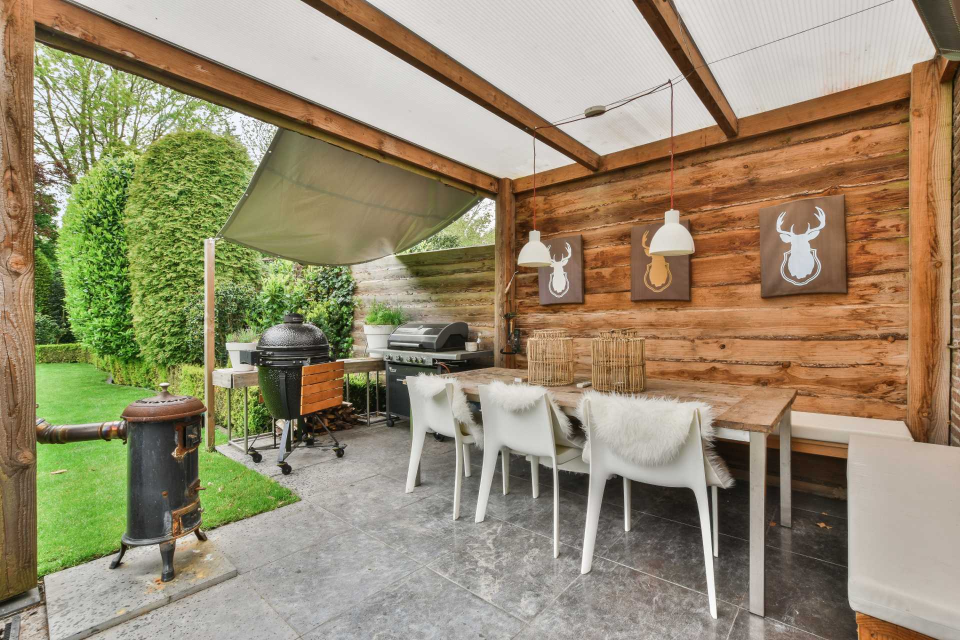 Covered outdoor kitchen with barbecue, dining table and garden view