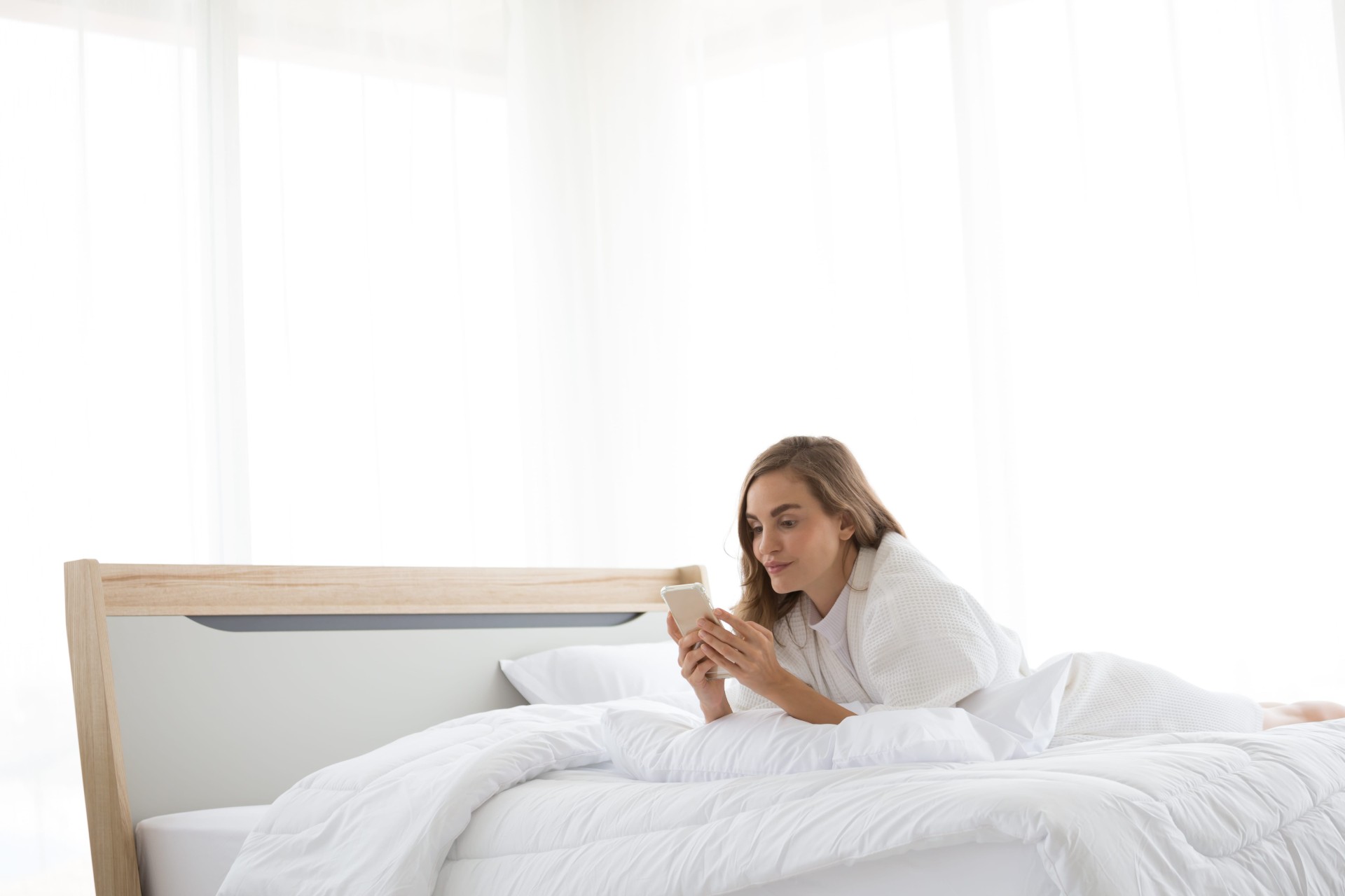 Woman lying in bed browsing on her phone