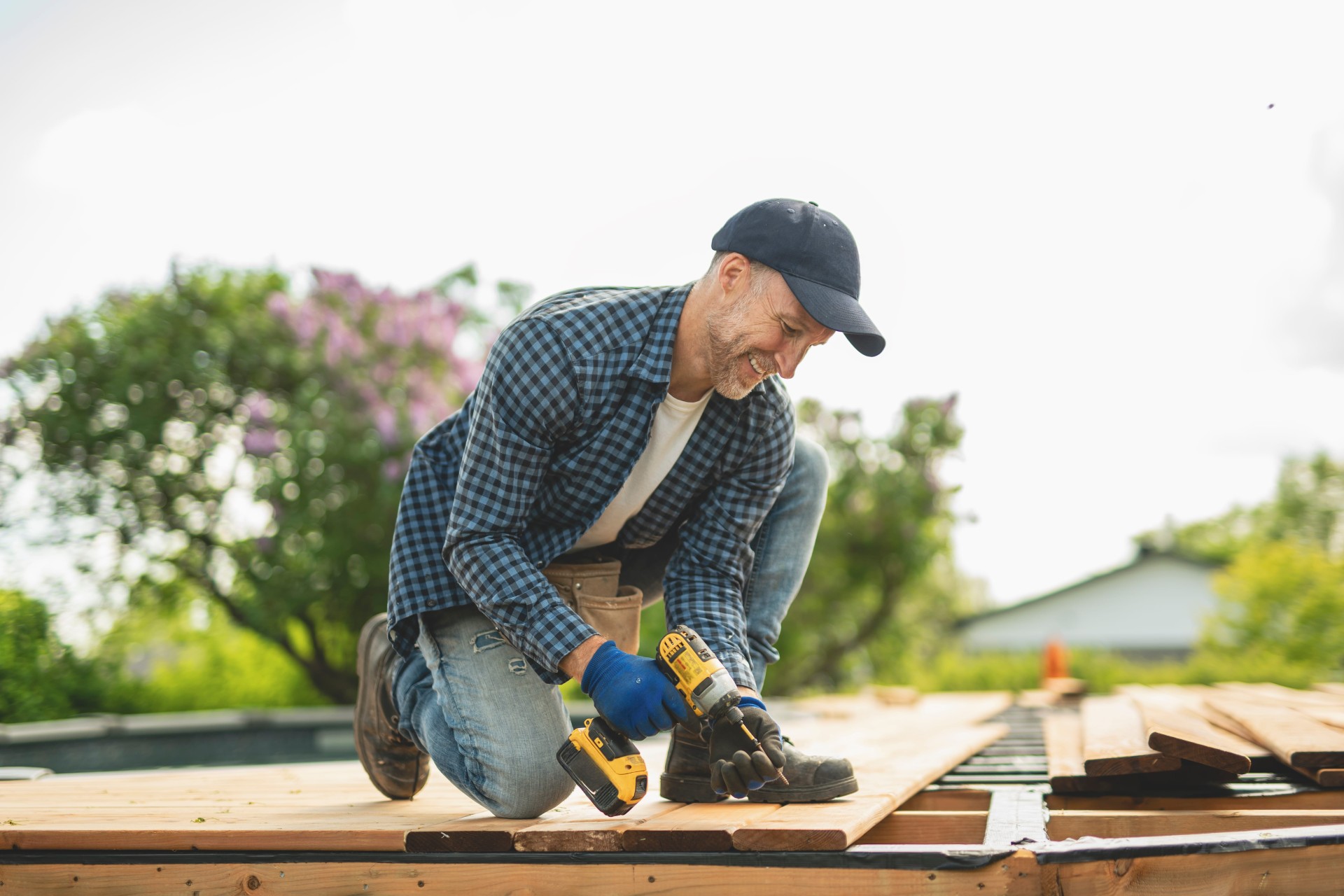 man building a wooden deck with a drill