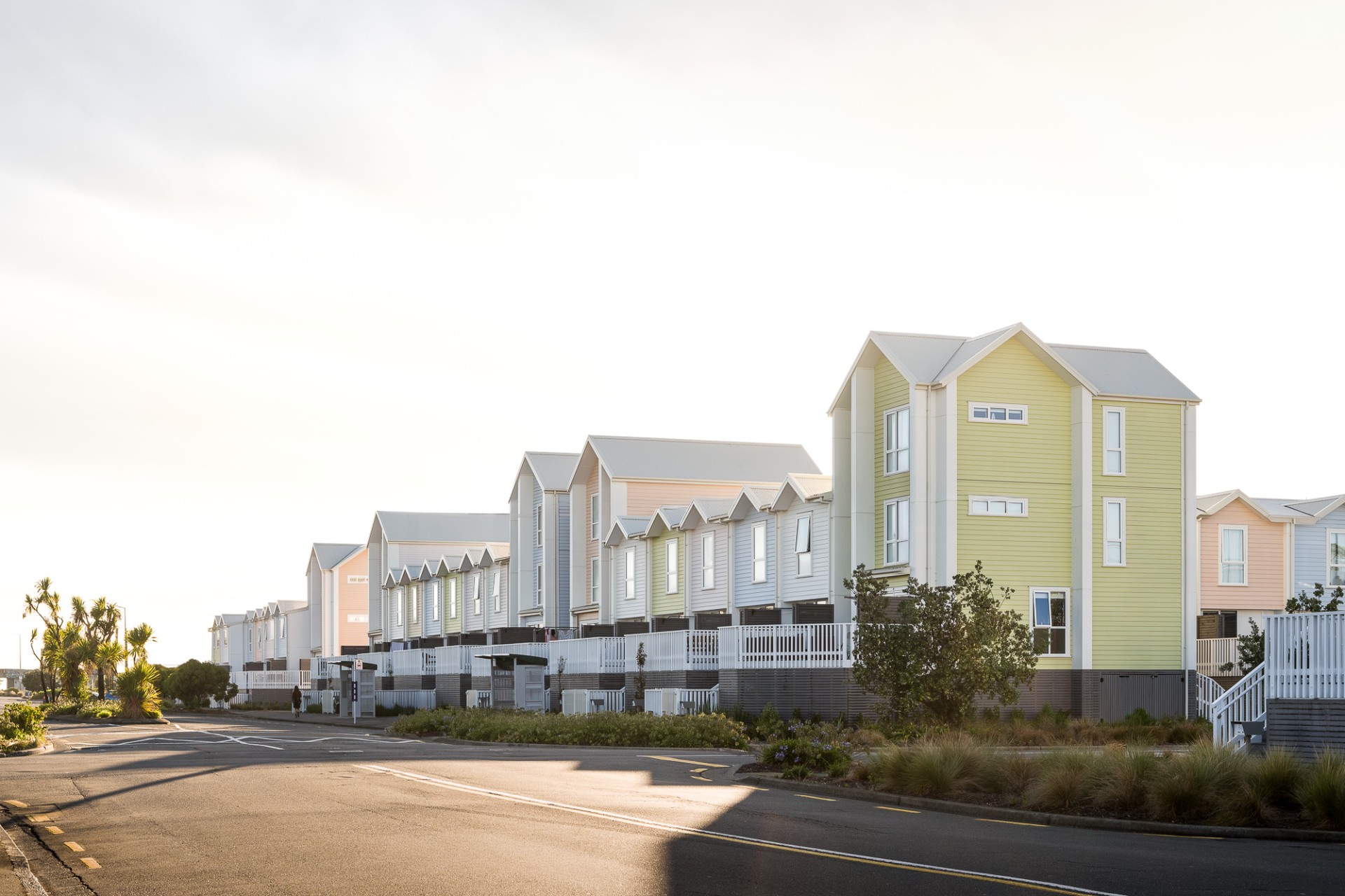 Row of pastel townhouses along a quiet street at sunset