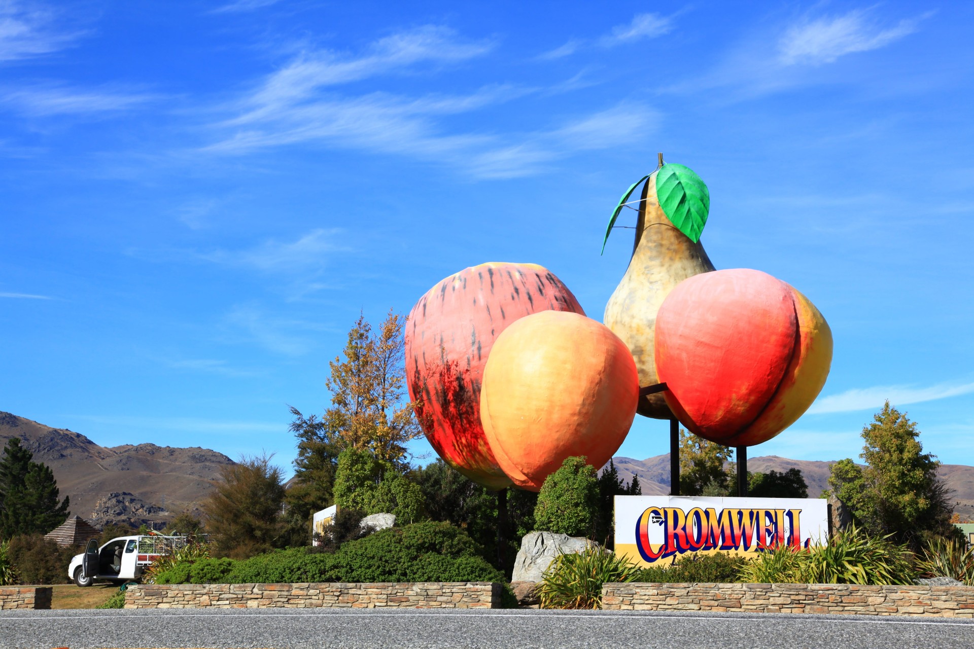 Giant fruit sculpture and Cromwell sign under a blue sky in Central Otago