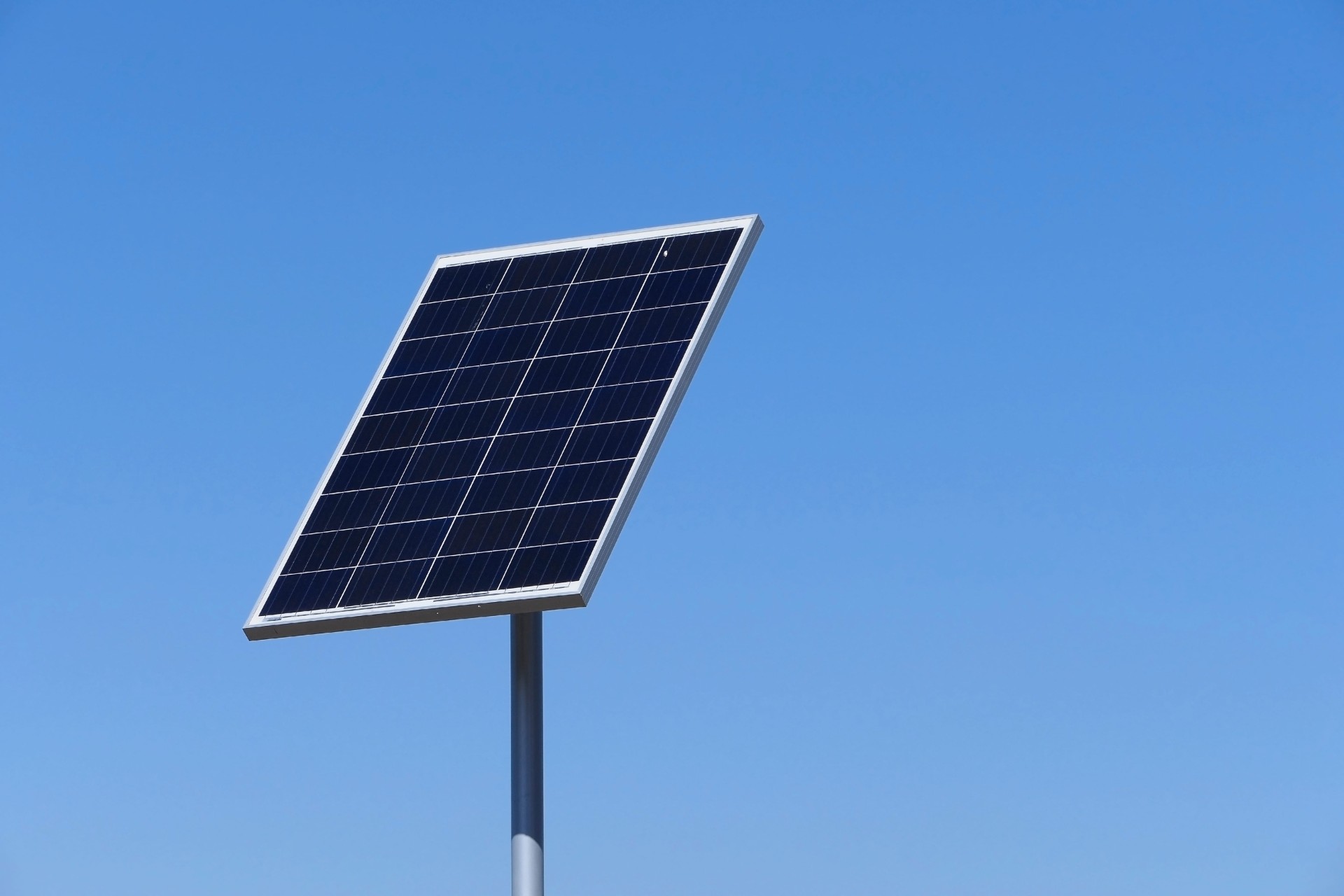 Solar panel mounted on a pole under a clear blue sky