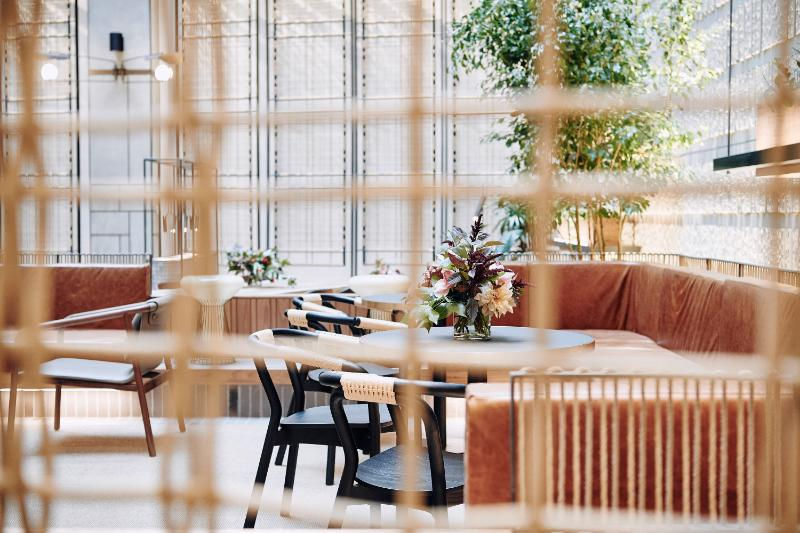 Interior office space with curved seating, wooden screens, tables, and indoor plants