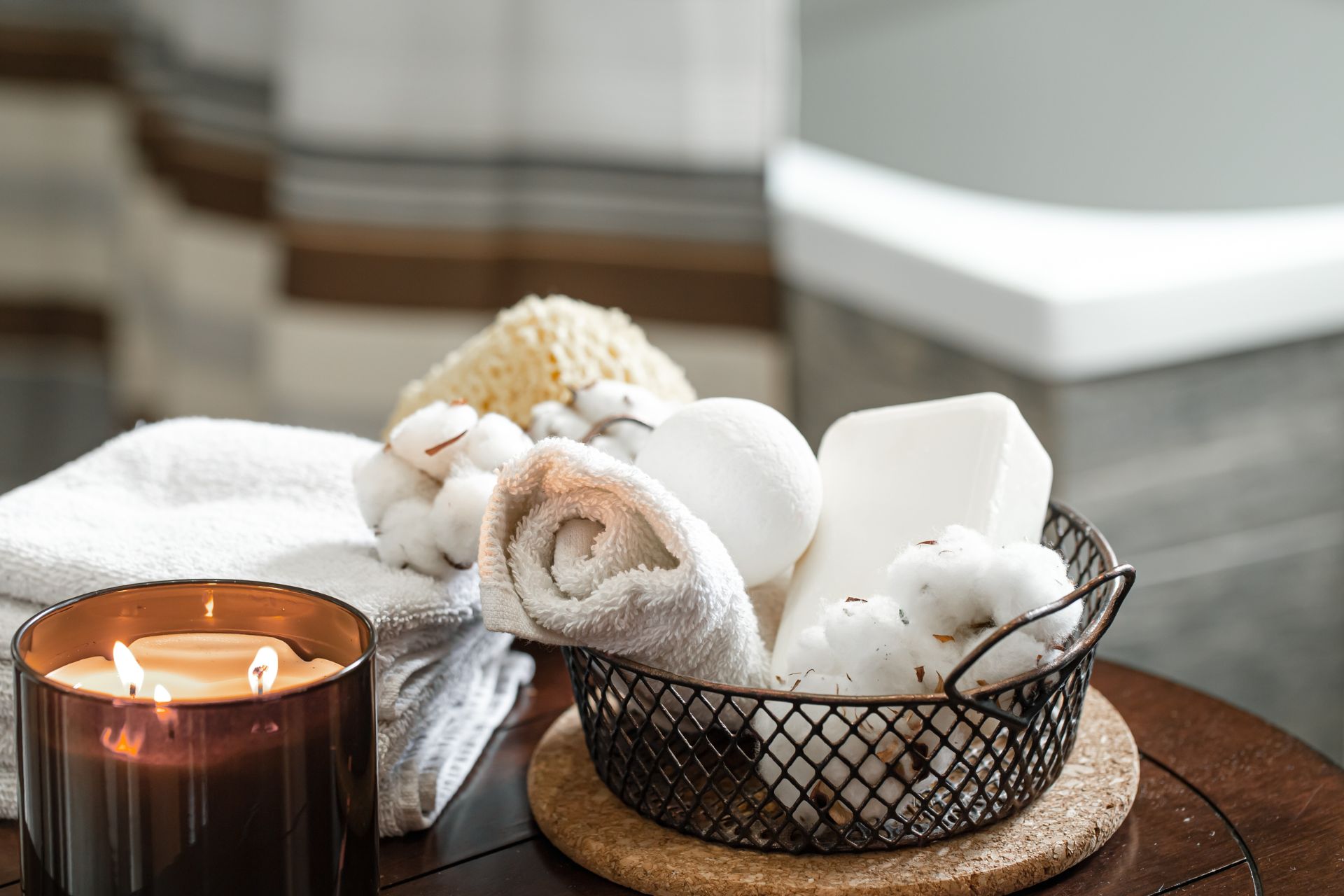 Spa corner with burning candles, rolled towels, and bath accessories creating a relaxing home bathroom atmosphere