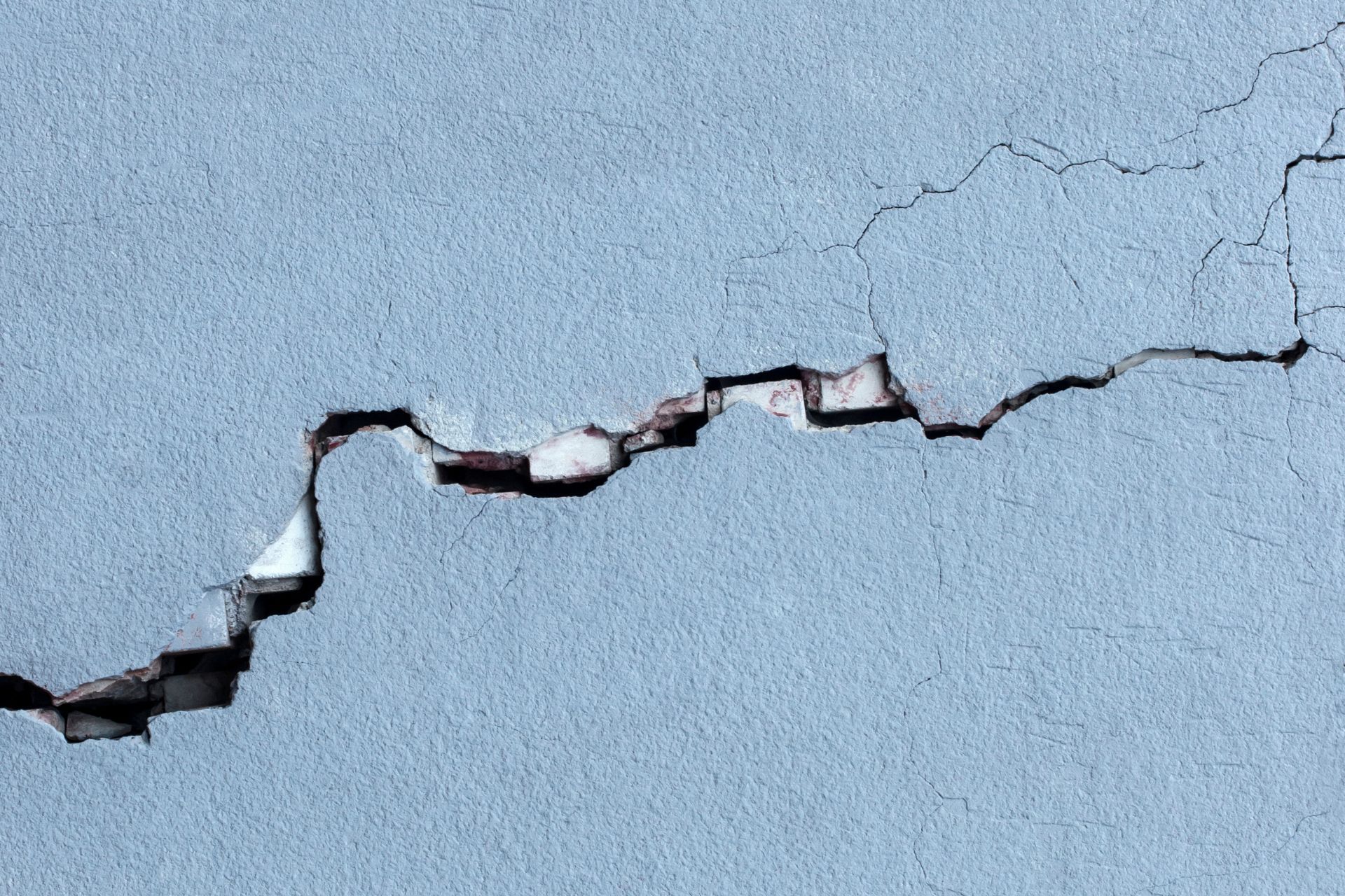 **Alt Text:** Cracked wall showing structural damage caused by earthquake movement and building deterioration.