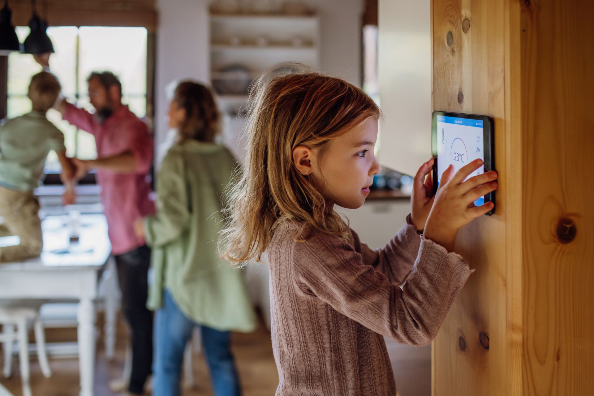 Girl adjusting a tablet mounted on a wooden wall in a modern family home