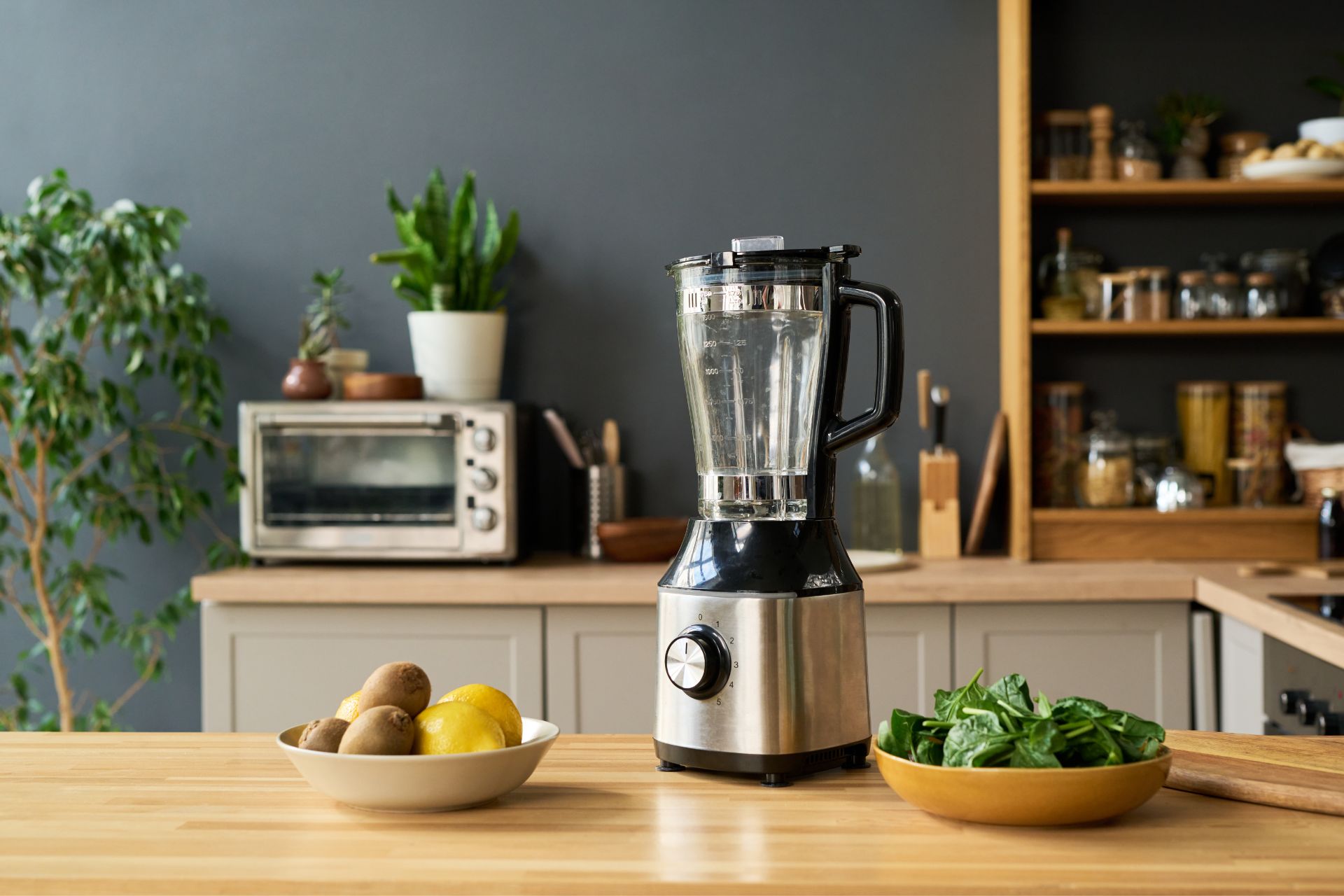 Blender and fresh ingredients arranged on a wooden kitchen counter, ready for preparing a healthy meal