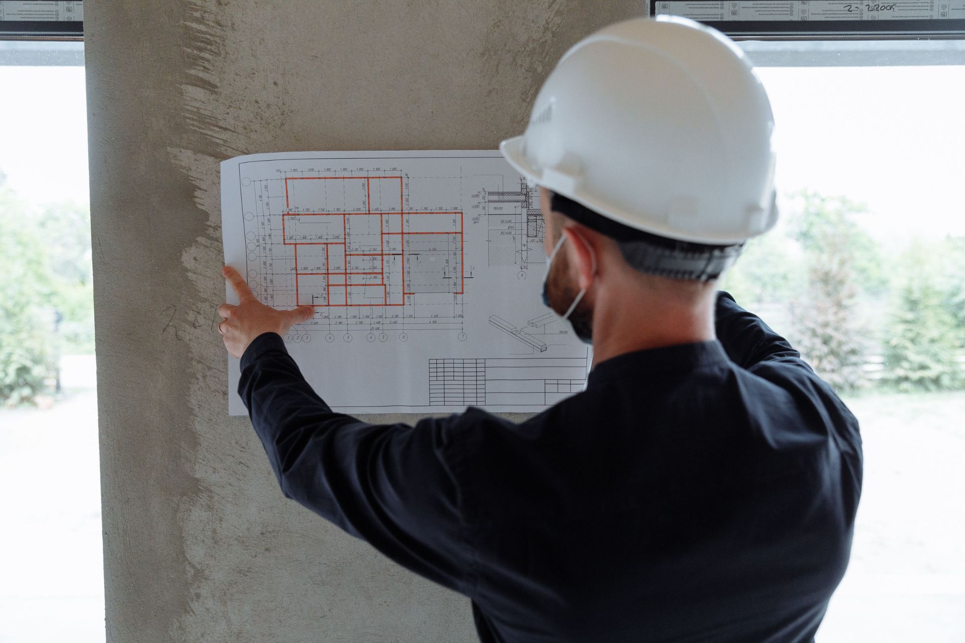Construction professional reviewing building plans inside a house under construction.