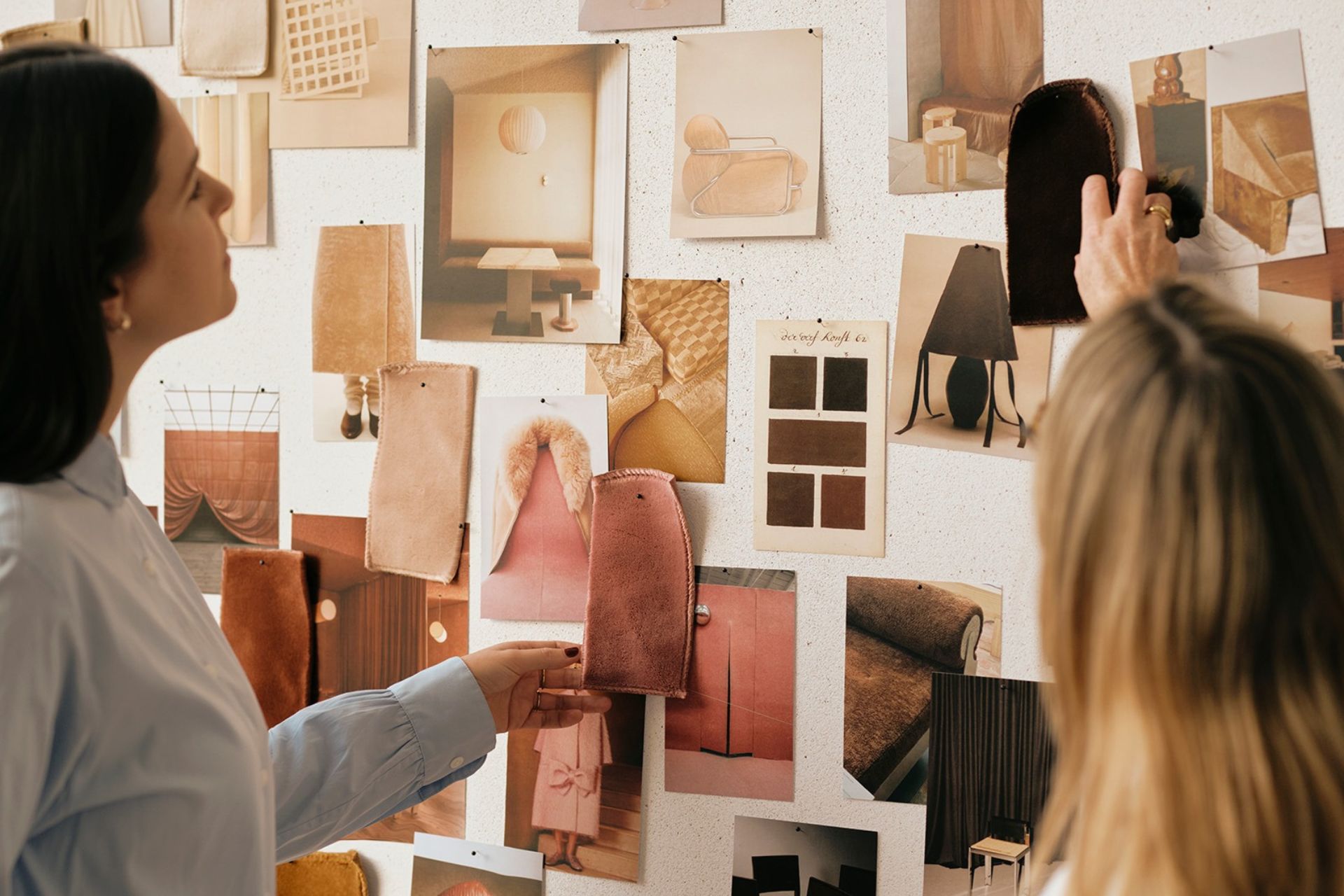 Two designers examine fabric swatches and interior design inspiration for a warm, textured home.