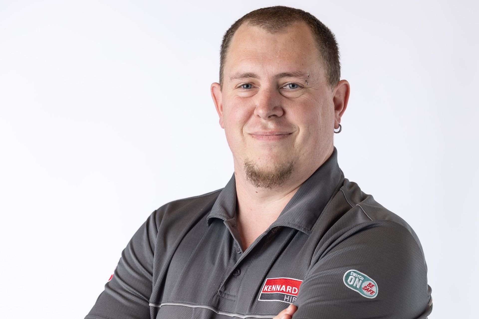 Ethan Booth-Holes, branch manager at Kennards Hire Whangārei, standing with his arms crossed in a grey work polo.