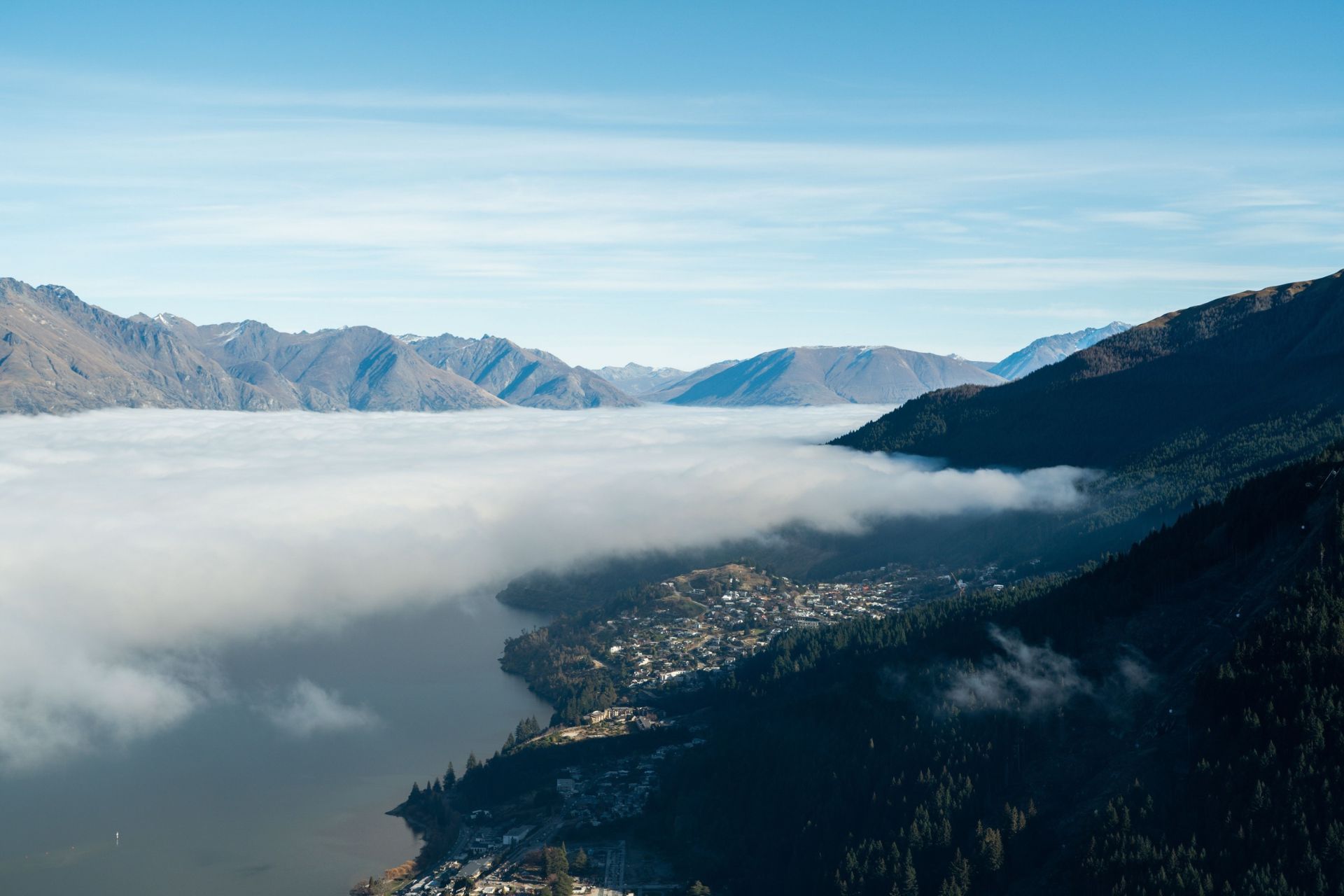 Queenstown homes nestled between a misty lake and surrounding mountains.